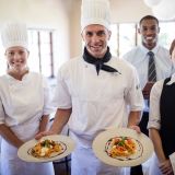 happy-male-chefs-holding-plates-with-prepared-food-in-hotel-e1702357319357.jpg