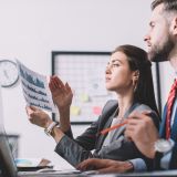 side-view-of-data-analysts-using-charts-while-assessing-risk-in-office-e1702358938897.jpg