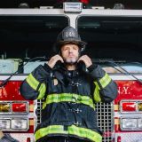 usa-new-york-portrait-of-firefighter-putting-on-helmet-in-front-of-fire-engine-e1706460494217.jpg